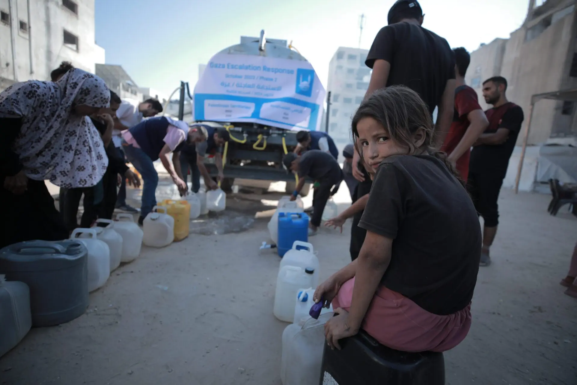 Children and adults wait to collect water from an Islamic Relief distribution on 5 August